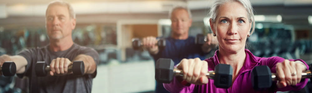 Group of older men and women lifting dumbbells as part of a workout class